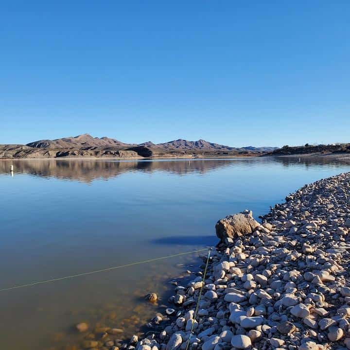 Caballo Lake, a serene lake tucked amidst majestic mountains and adorned with scattered rocks, offers a breathtaking view of nature's wonders at Caballo Lake State Park.