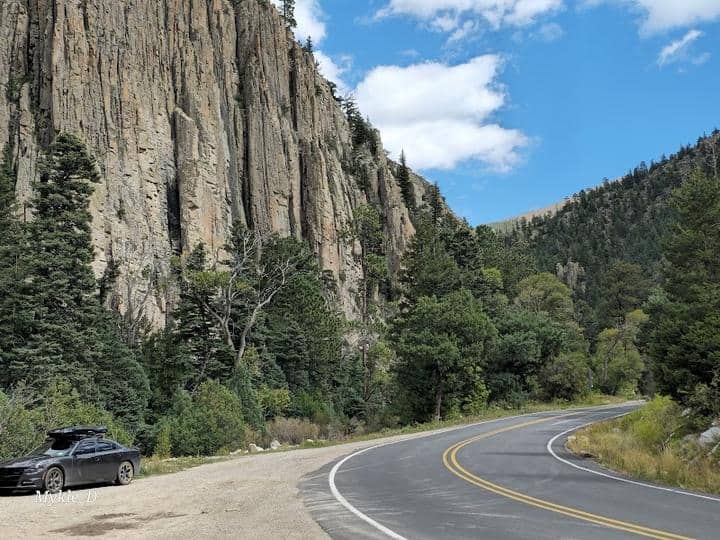 A car is parked on the side of Cimarron Canyon State Park, a mountain road.