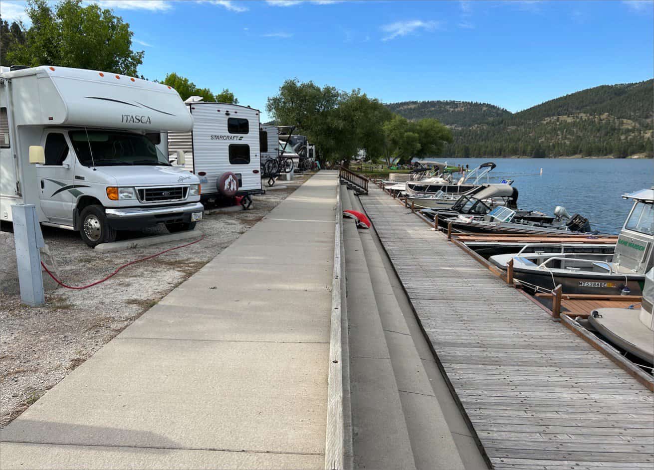 Rvs parked beside a lake with a dock and moored boats at Black Sandy State Park.