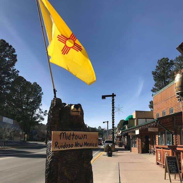 A statue of a bear with a flag in front of it at Midtown Mountain Campground.