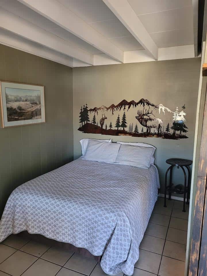 A bed or beds in a room at Horseman's Bunkhouse with a mural on the wall.
